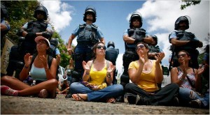 Students protesting budget cuts at the University of Puerto Rico, San Juan campus.  Riot police officers stand behind them.  (Photo: Ricardo Arduengo / Associated Press)