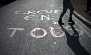 A woman walks past a message written on a road saying "Tous en greve" (everybody on strike) as part of the demonstrations by railway workers from state-run company SNCF during the nationwide day of protest against pension reform on October 13, 2010 in Chenove, eastern France. (Photo: Jeff Pachoud / AFP / Getty Images)