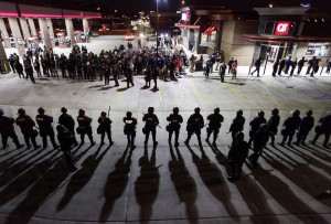 Police officers in riot gear hold a line as they watch demonstrators protest the shooting death of Michael Brown and 18-year-old Vonderrit Myers Jr. in St. Louis, Missouri on October 12, 2014.  (Photo: Joshua Lott / AFP / Getty Images)