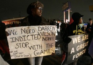 Protesters hold signs Saturday, Nov. 22, along a stretch of road where protests occurred following the August shooting of Michael Brown, an unarmed black teenager, by a white police officer in Ferguson, Missouri.  (AP Photo / Charlie Riedel)