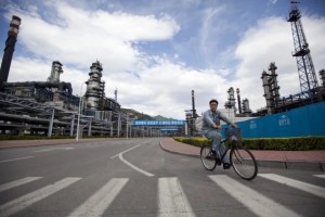 A worker cycles through the China Petroleum & Chemical Corp (Sinopec) refinery in Beijing. (Photo: Nelson Ching / Bloomberg)